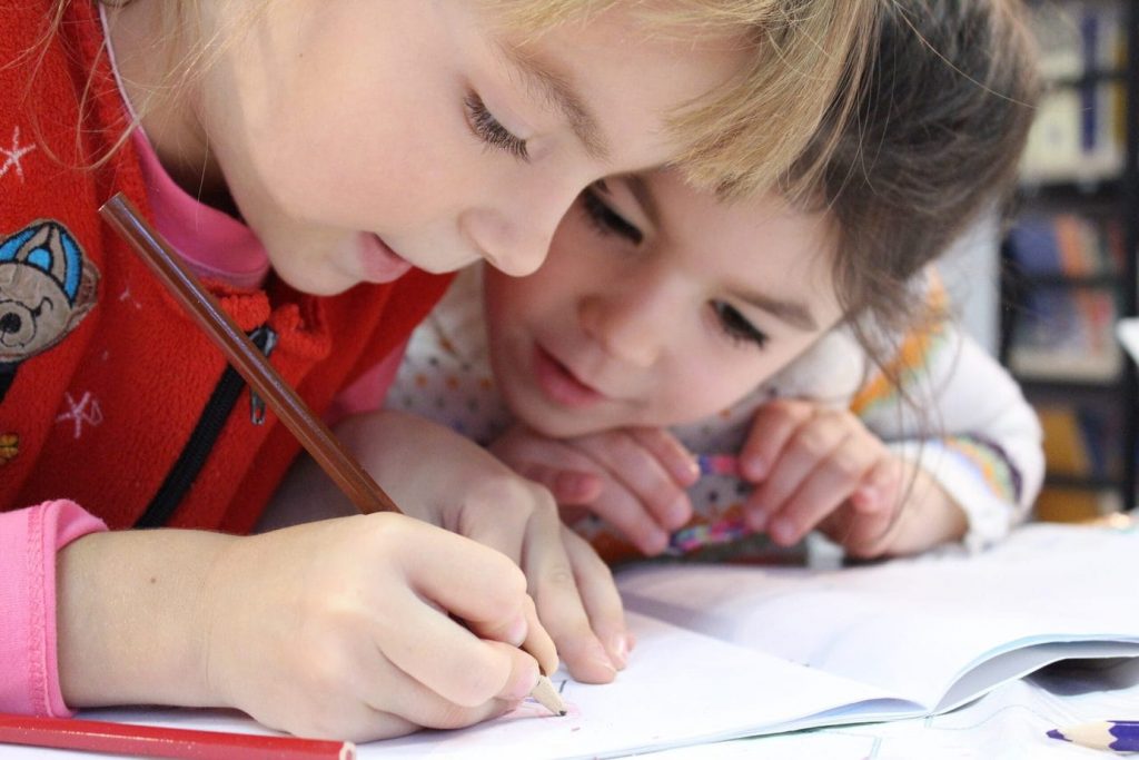 Two girls writing their ideas. Keeping the students involved in all stages of the process can help them remain enthused.